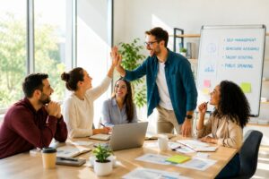 team di professionisti riuniti in un meeting di management in un ufficio moderno, due colleghi si scambiano il cinque, mentre gli altri partecipano con entusiasmo. sullo sfondo si vede una lavagna con i 4 temi formativi: self-management, benessere aziendale, talent scouting e public speaking. l'immagine rappresenta collaborazione e crescita personale.